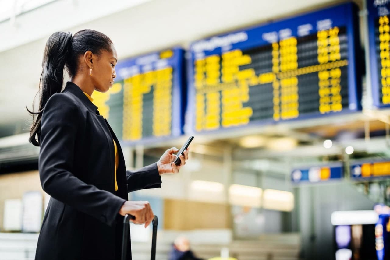 Traveller checking her phone beneath the departures board